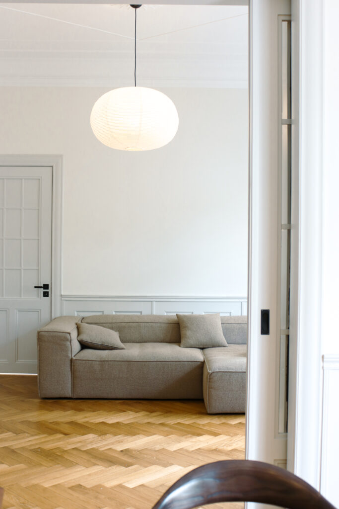 Wohnzimmer einer sanierten Altbauwohnung mit Blick auf Essbereich